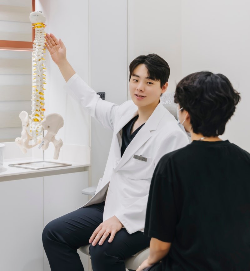 정성연 대표원장이 척추 모형으로 환자에게 상태를 설명하는 모습